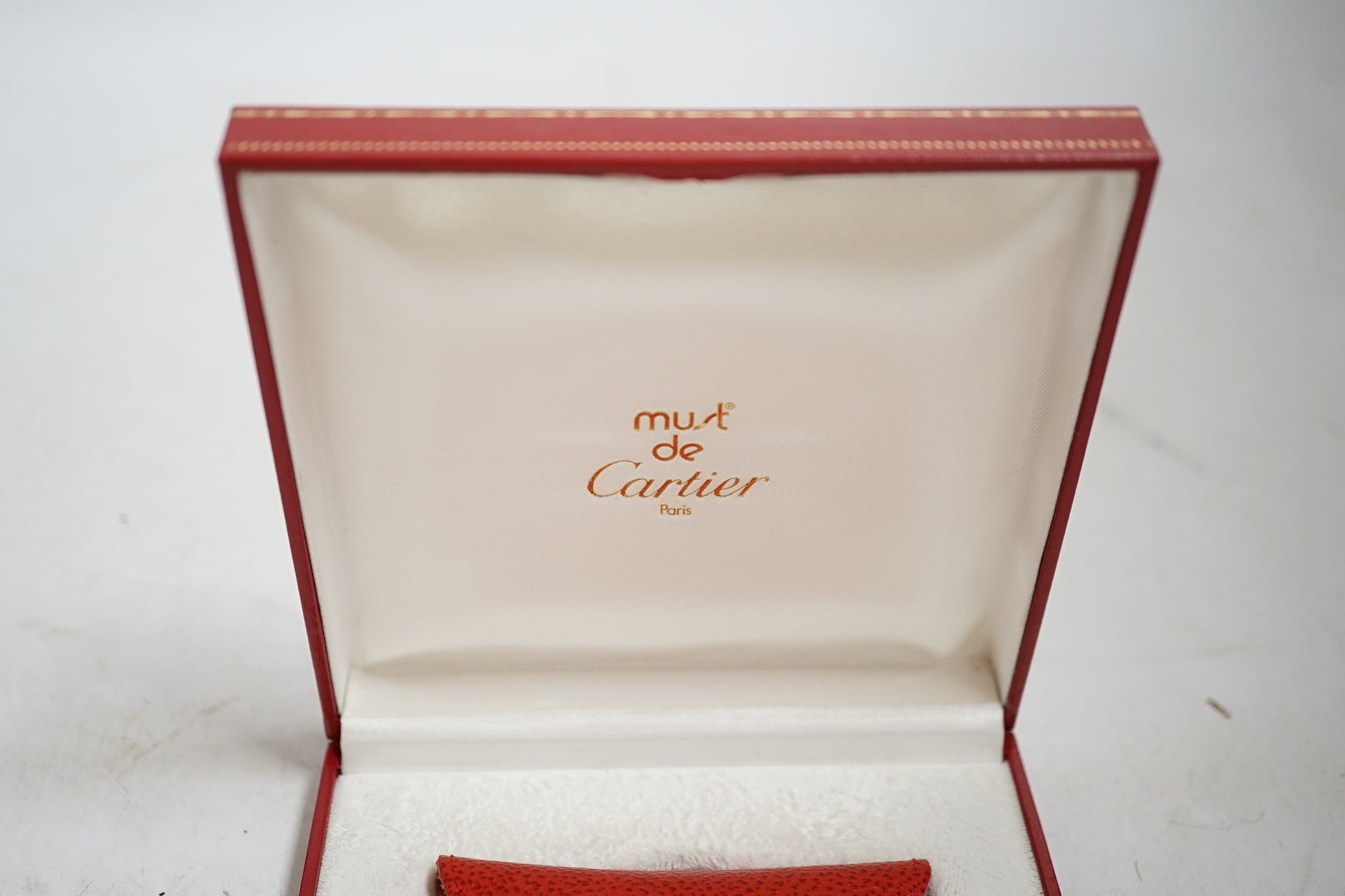 A Must de Cartier travelling alarm clock with pouch and case, 6cm wide. Condition - good, not tested